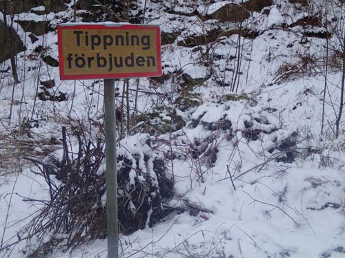 Som vanligt ligger det en hög med trädgårdsavfall bakom denna typ av skylt...