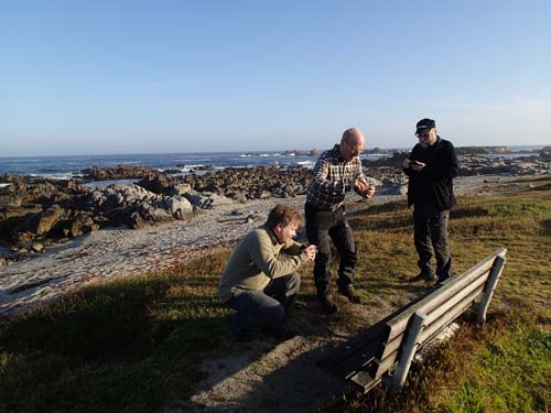 Tre män vid en bänk med utsikt, ingen bryr sig om havet, alla tittar på bänken - är det inte typiskt för burkjägare?